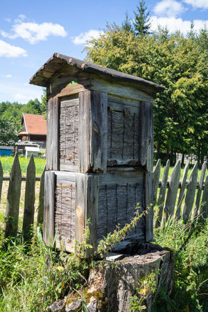 A wooden structure with a roof sits in a field. The structure is old and has a rustic appearanceの写真素材