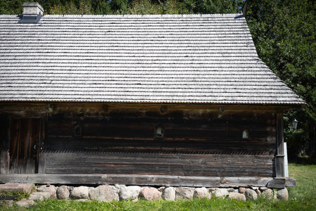 A large, old building with a slanted roof. The roof is made of wood and has a lot of shingles. The building is surrounded by a grassy areaの写真素材