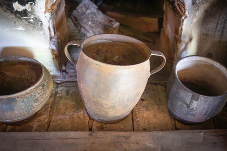 Three old pots sit on a wooden shelf, one of which is a large, rusty pot. The other two are smaller, and they all appear to be old and worn. The scene gives off a sense of nostalgia and historyの写真素材
