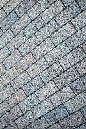 A brick wall with a gray and white color. The wall is made of bricks and has a pattern of white and...