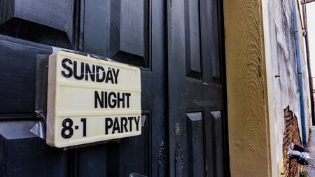 Black door in a back alleyway with a sign advertising a partyの写真素材