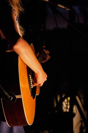 A woman playing a guitar during a concert with a perfect luminance.