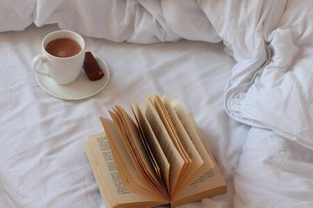 An open book and a Cup of tea on the white bedの写真素材