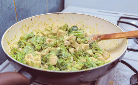 preparing broccoli with pieces of chicken breastsの写真素材