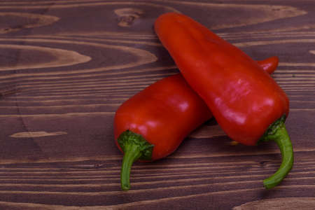 two red peppers on a wooden boardの写真素材