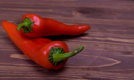 two red peppers on a wooden boardの写真素材
