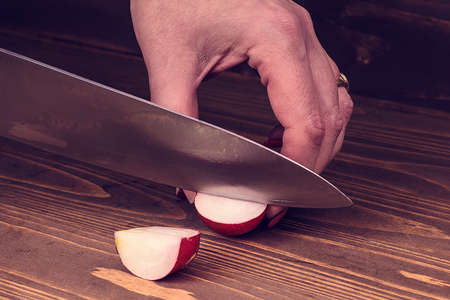 woman's hand cut radishes on a wooden boardの写真素材