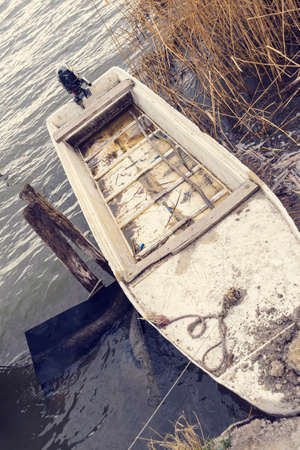 An old plastic fishing boat by the lakeの写真素材