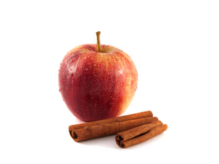 Isolated wet red apple with cinnamon pods on a white background. Fresh diet fruit. Healthy fruit with vitamins.の写真素材