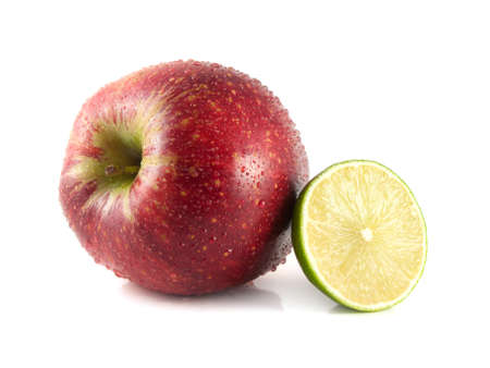 Isolated big red apple with half of lime on a white background (water drops). Fresh diet fruit. Healthy fruit with vitamins.の写真素材