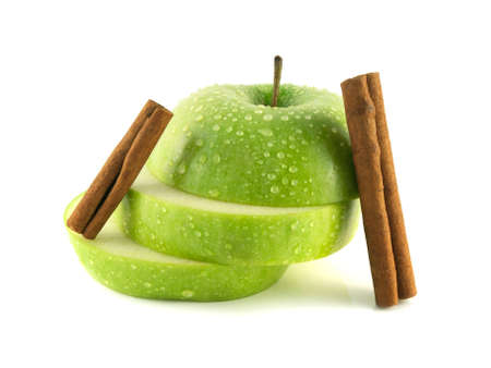 Isolated green apple slices with cinnamon pods (white background). Fresh diet fruit (water drops). Healthy fruit with vitamins.の写真素材