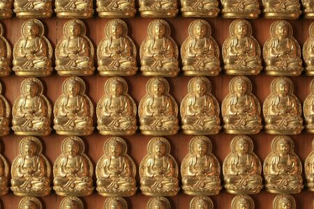 Gold Buddha sculptures on the wall inside Chinese temple の写真素材
