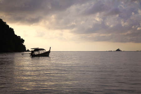 Silhouette scene of long-tailed boat on the sea at dawn の写真素材