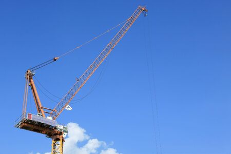 Yellow tower crane against blue sky の写真素材