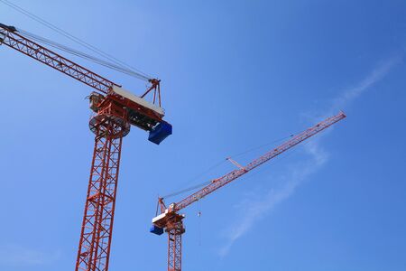 Two red tower cranes  against blue skyの写真素材