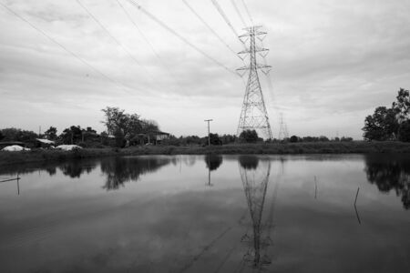 High voltage transmission towers near the pondの写真素材