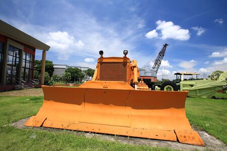 Yellow excavator on the grass against blue skyの写真素材