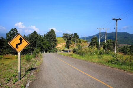 Curved Traffic sign on local street against blue skyの写真素材