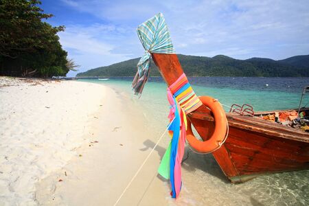 Long tail wooden boat with colorful ribbons on the beachの写真素材