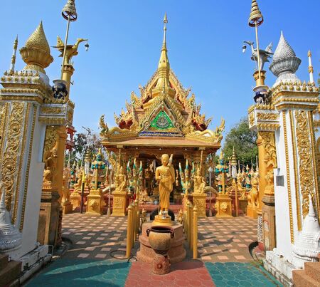 Gold Buddha statue with beautiful temple architecture at the entrance of Wat Tai-Phra-Chao-Yai-O ng-Tue temple in Ubonratchathani, Thailand の写真素材
