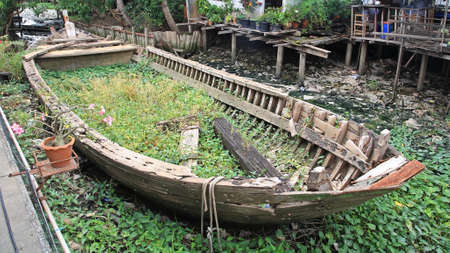Rotted and abandoned row wooden boat at Thai villageの写真素材
