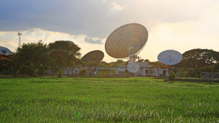 Satellite communication dish against flare light at sunsetの写真素材