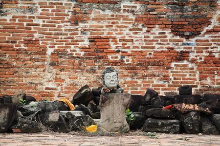 Buddha statue without arms and legs in front of grunge wall in Ayutthaya, Thailandの写真素材