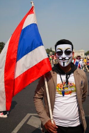 BANGKOK-DEC 9: Unidentified Thai protester wearing  Guy Fawkes mask with Thai flag on December 09, 2013 in Bangkok, Thailand. Millions of Thai people rally from many streets to expel government today.のeditorial素材