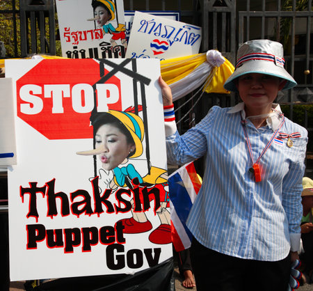 BANGKOK-DEC 9: Unidentified Thai protester shows anti Yingluck government plate on December 09, 2013 in Bangkok, Thailand. Millions of Thai people gather at government house to expel government today.のeditorial素材