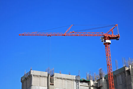 Red crane at Construction site against blue skyの写真素材