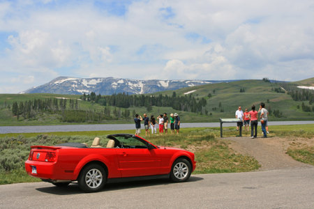 WYOMING, USA - JULY 06, 2008: Red sport car parking and unidentified people visiting Yellowstone lake viewpoint. Here is the first national park in the world.のeditorial素材