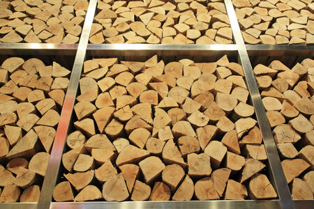 Tall stack of firewood logs on iron storage for winterの写真素材