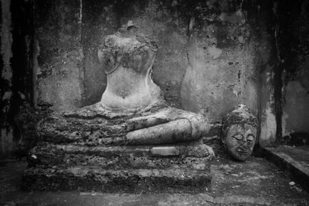 Ancient Buddha head cut near the body at Srisatchanalai historical park in Sukhothai, Thailandの写真素材