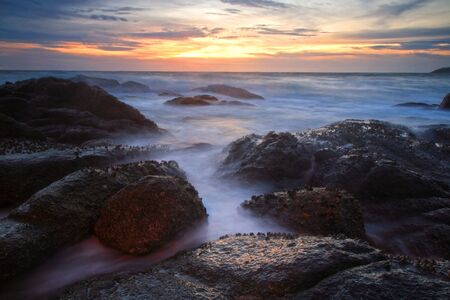 Seascape of motion wave hit the rock with twilight sky at Karon beach, Phuket, Thailandの写真素材