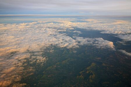 View of clouds from the window of aircraft. Flying above the clouds at sunriseの写真素材