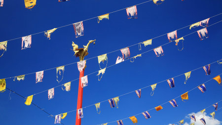 Golden bird statue on the top of red pole with many Thai flags