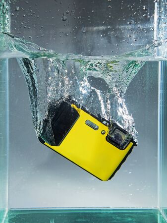 waterproof digital camera dropped in container water with splashの写真素材