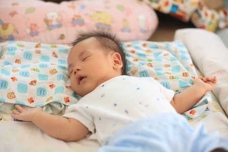 Cute asian newborn baby boy sleeping on a bed, 2 months oldの写真素材