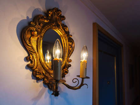 Antique lamp and mirror on the wall near a doorの写真素材