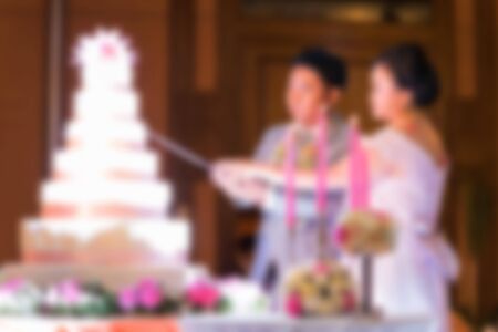 blurred image of bride and groom cutting wedding cakeの写真素材