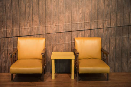 Brown leather chair and table near wooden wall backdropの写真素材