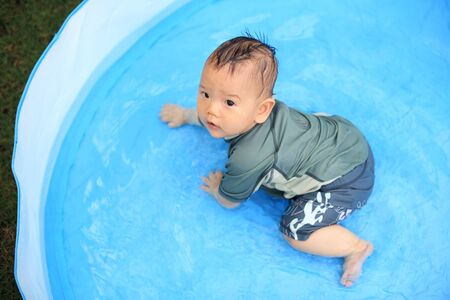 Happy son baby play water in kid inflatable poolの写真素材