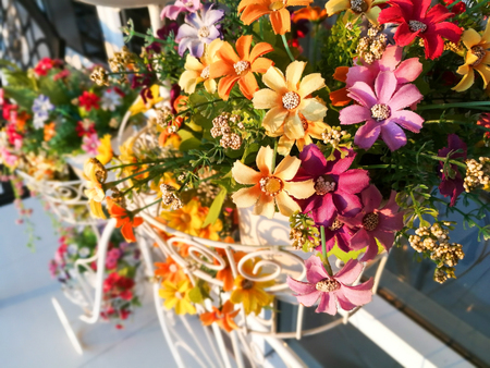 Fake colorful flowers on bicycle basket for garden decorationの写真素材