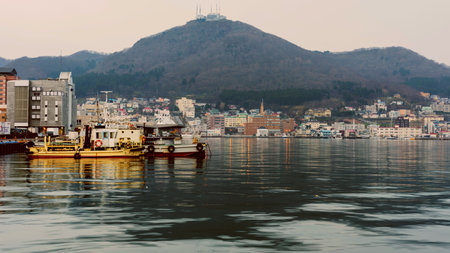 HAKODATE, JAPAN - APRIL 22, 2016: Fishing boats at the Port and urban city near Mt. Hakodate in the morning.のeditorial素材