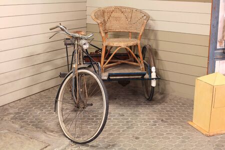 Antique old tricycle with old wooden chairの写真素材