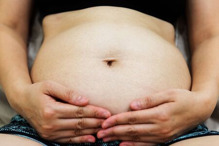 Closeup of 13 weeks pregnant Belly with mother handsの写真素材