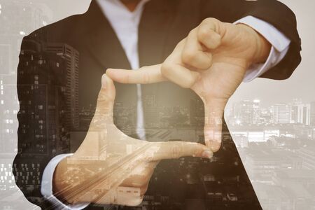Double exposure, business man thumb and forefinger connect overlay with modern city architectureの写真素材