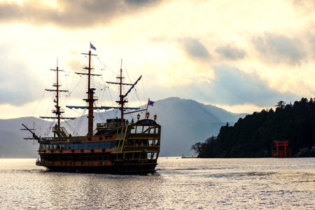 HAKONE, JAPAN - MAY 4, 2017: sight seeing pirate ship on Ashi lake with torii gate of Hakone shrine against sun rays before sunset.のeditorial素材