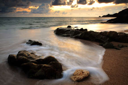Beautiful seascape at sunset with motion sea wave touching rock at Kalim beach, Phuket, Thailandの写真素材