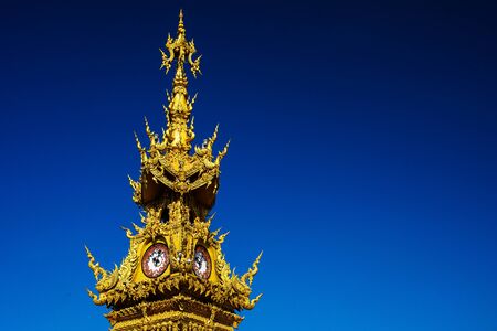 Golden clock tower against blue sky, Chiang Rai, Thailandの写真素材